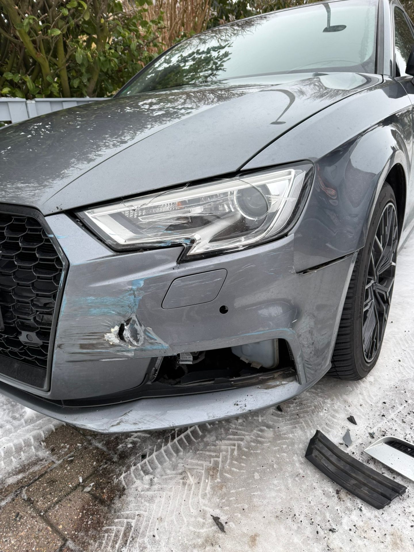 Frontschaden an einem grauen Audi A3 — beschädigter Stoßfänger und Scheinwerfer