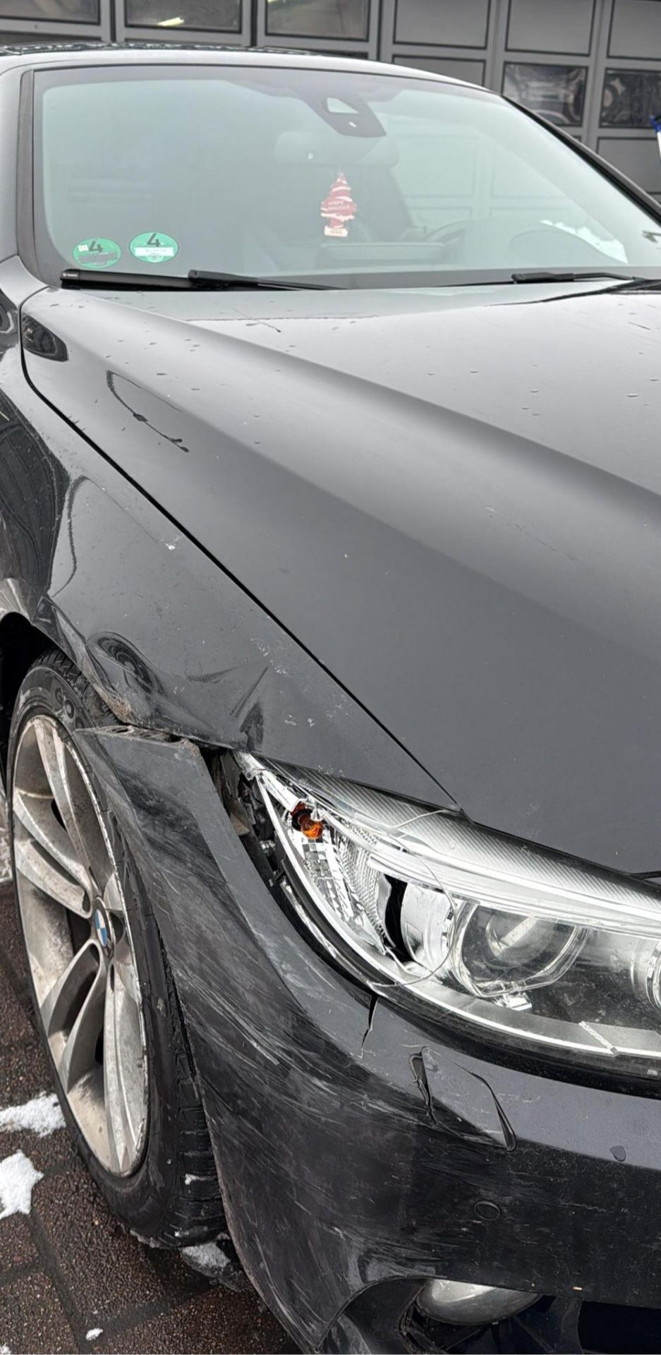 Frontschaden an einem schwarzen BMW nach Kollision — beschädigter Stoßfänger, Scheinwerfer und Kotflügel